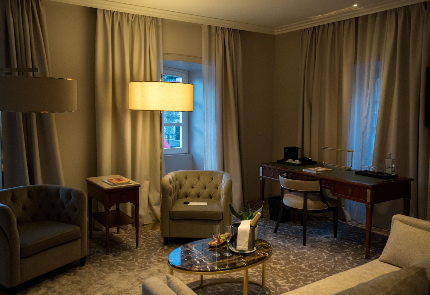 A hotel room with a work desk and seating